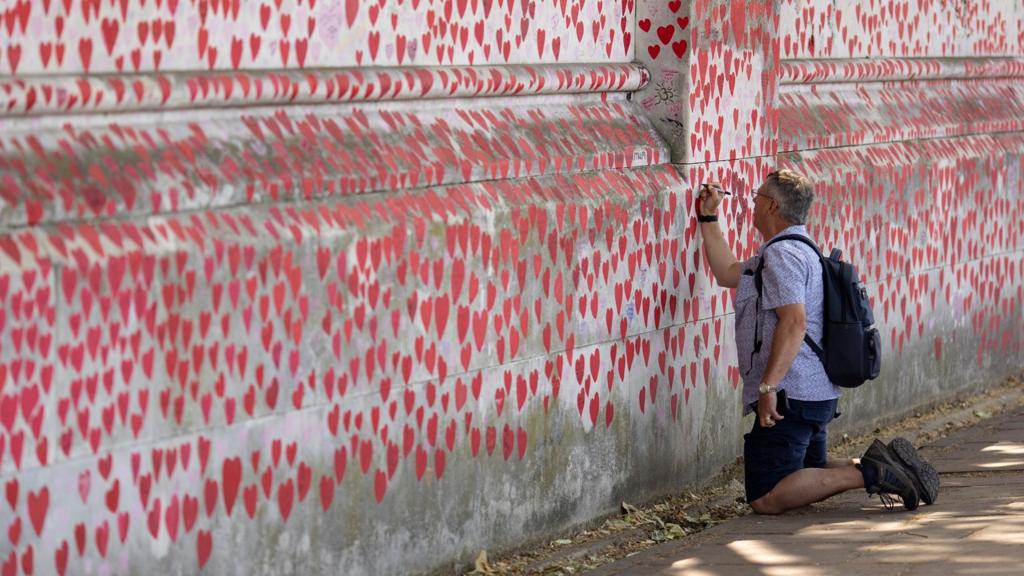 A man writes on the National Covid Memorial Wall in London