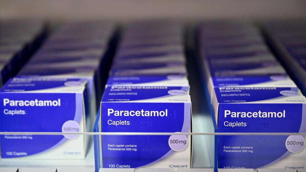 Boxes of blue paracetamol packaging on a shelf.