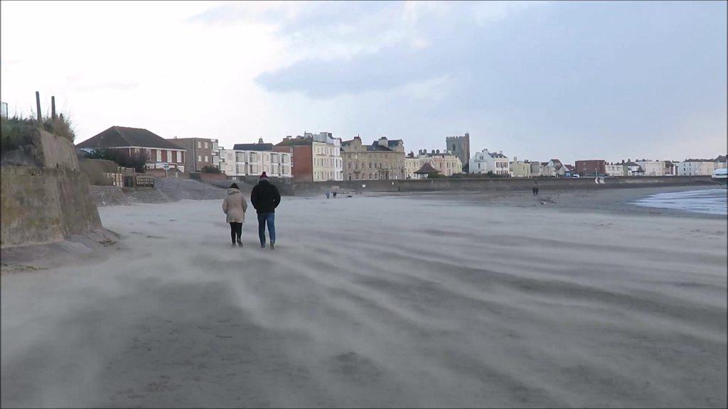 Two people walk across Burnham-on-Sea seafront during the high winds