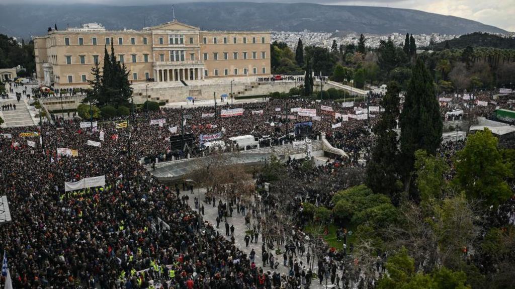 Greeks stand in the rain in the centre of Athens 