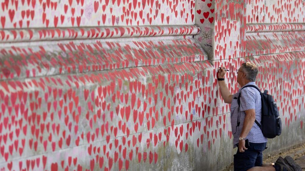 A man writing on the National Covid Memorial Wall