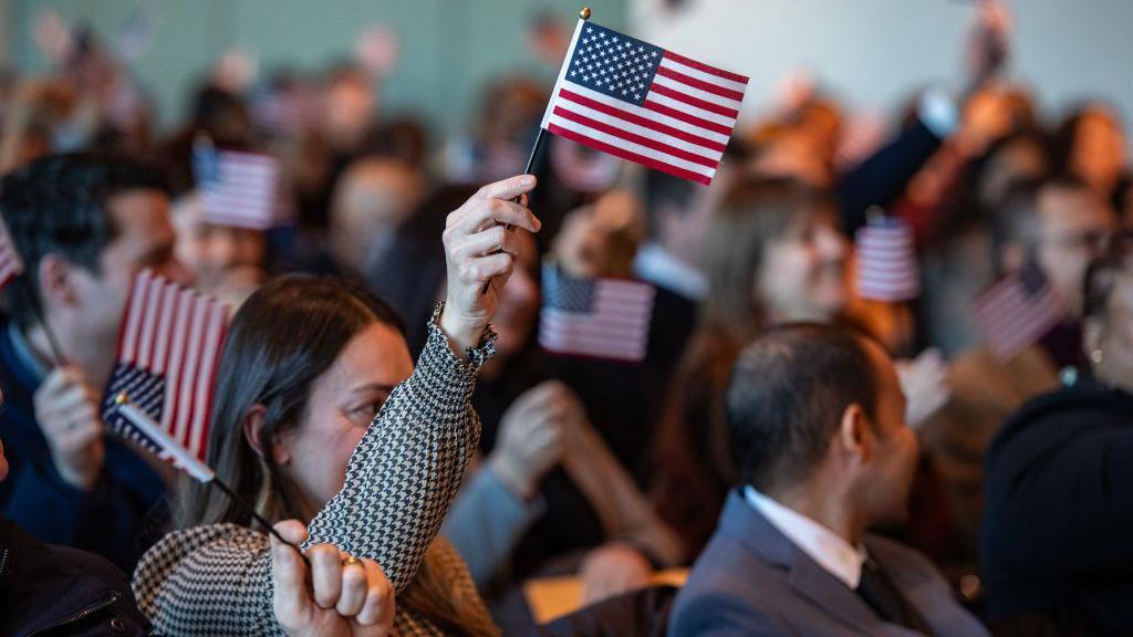 A woman waves a small US flag during a naturalisation ceremony