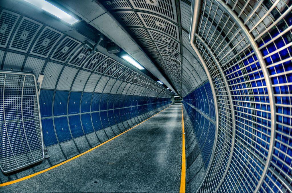 The distinct blue and grey steel with the yellow guide stripe running along the floor of a London Bridge station corridor