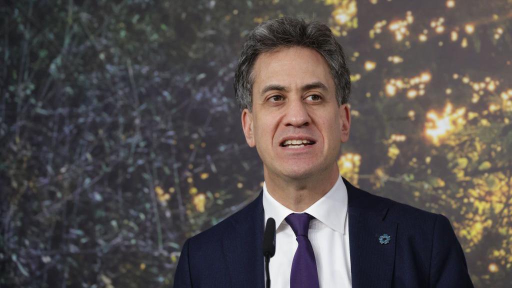 Ed Miliband speaking in front of a background of trees