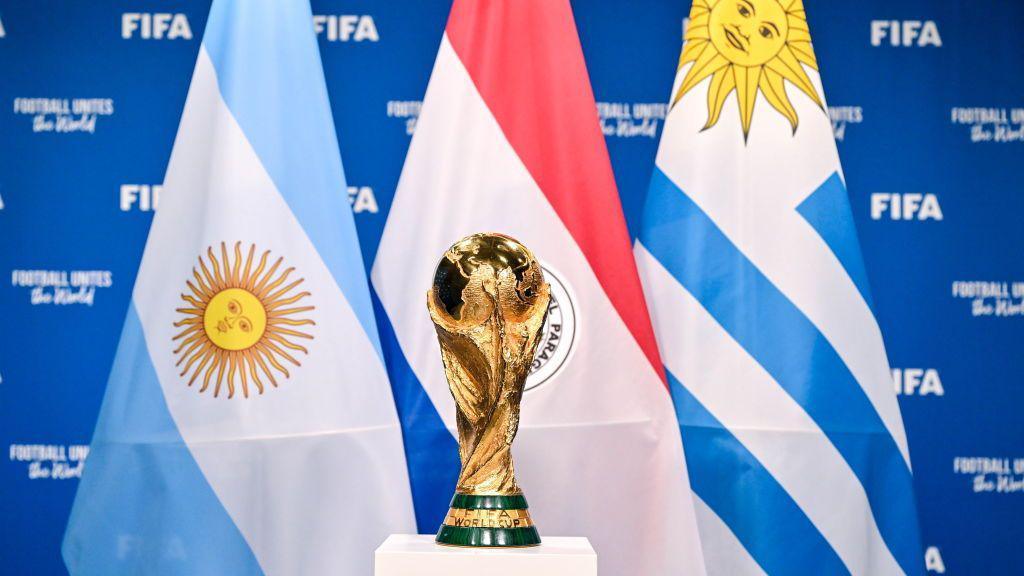 Fifa World Cup trophy standing in front of the flags of Argentina, Paraguay and Uruguay.