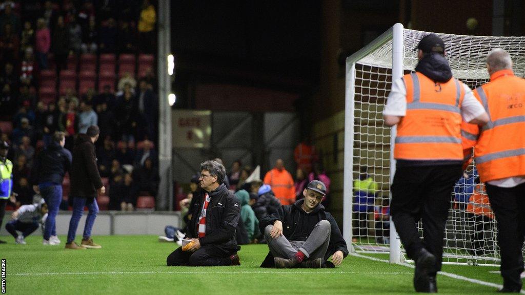 Leyton Orient fans sit in penalty area to try and get game stopped