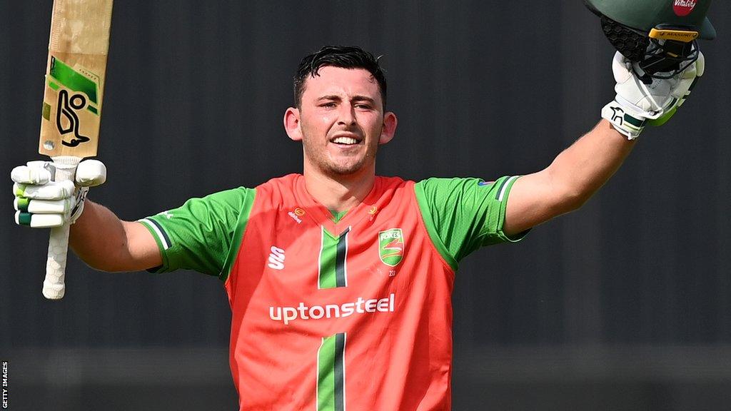 Harry Swindells holds up his bat and helmet after scoring a century in Leicestershire's One-Day Cup final win