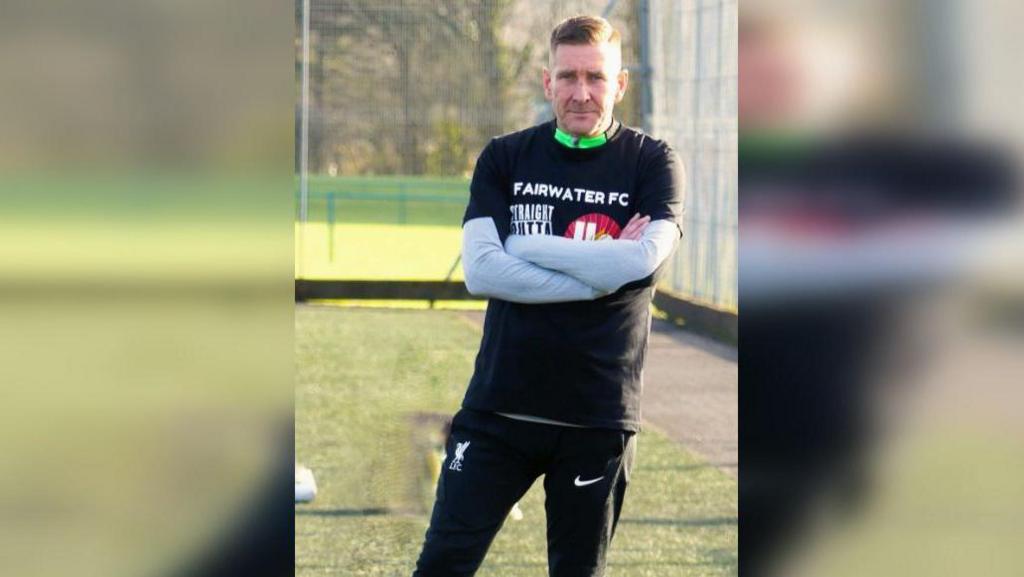 Scott Hartley yn kit ‘End Tragedy Chanting Now’ hefo’i dim blaenorol (Fairwater FC U’14s).