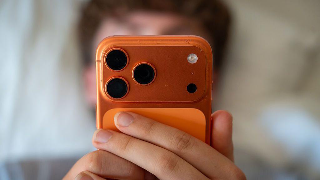 A person holding an orange mobile phone.