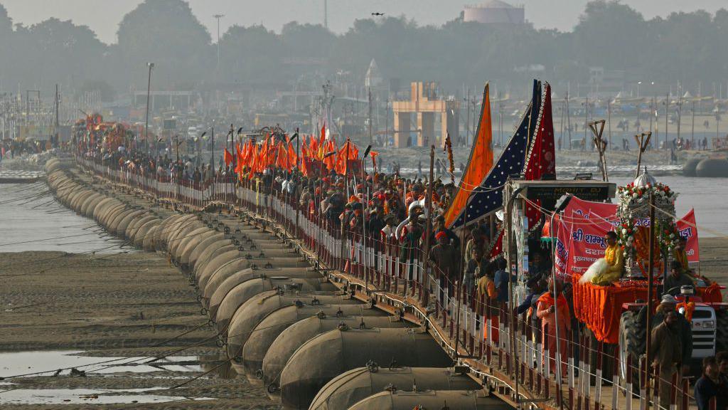 Hindu holy men or Sadhus walk in a religious procession of Atal Akhara across a floating pontoon bridge, ahead of the Maha Kumbh Mela festival in Prayagraj on January 1, 2025. (Photo by Niharika KULKARNI / AFP) (Photo by NIHARIKA KULKARNI/AFP via Getty Images)