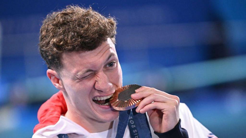 Noah WIlliams bites his bronze medal