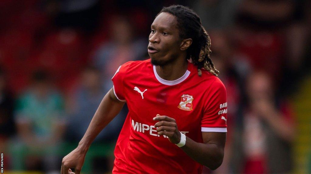 Tariq Uwakwe running with the ball on the pitch during a game for Swindon