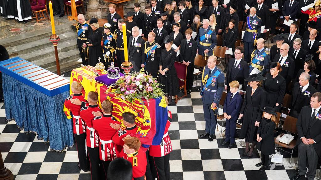 The coffin of Queen Elizabeth II, draped in the Royal Standard with the Imperial State Crown and the Sovereign's Orb and Sceptre, is carried by the bearer party