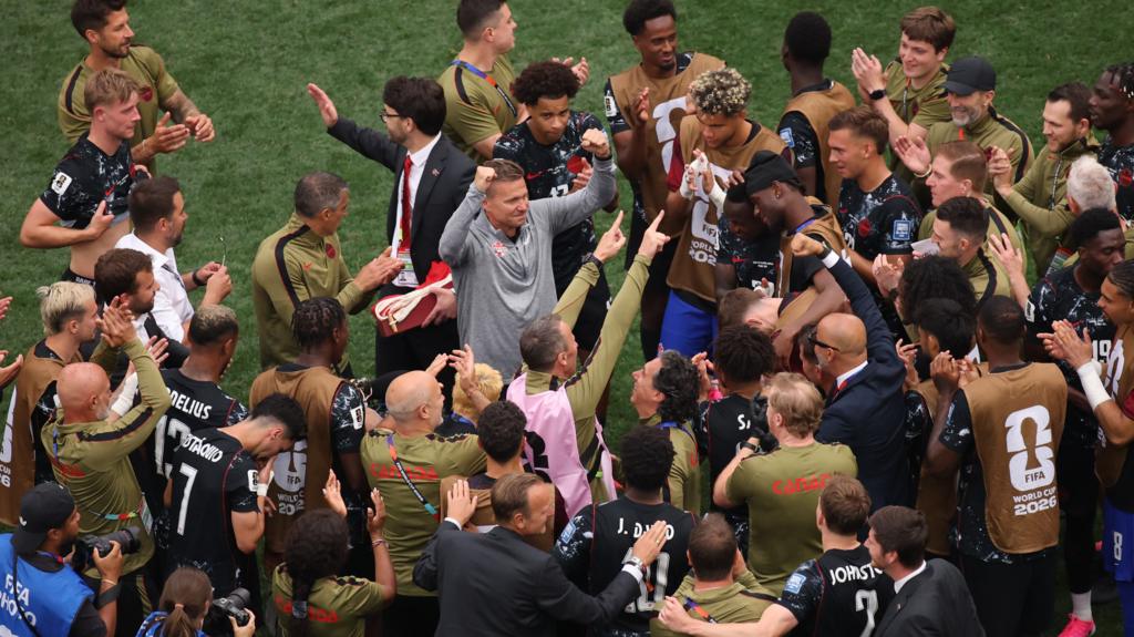 Canada players and staff in a huddle around manager Jesse Marsch who has his fists clench in celebration