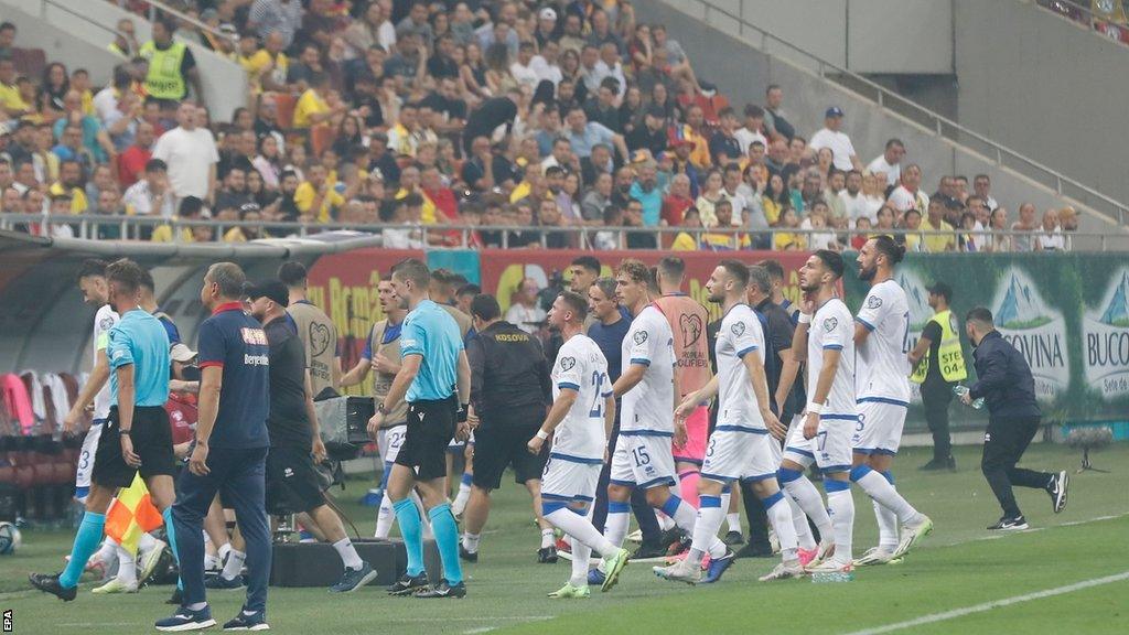 French referee Willy Delajod leads Romania and Kosovo players off the pitch