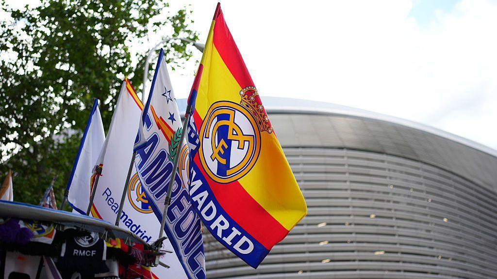 A row of Spain and Real Madrid flags fly in front of the Bernabeu stadium