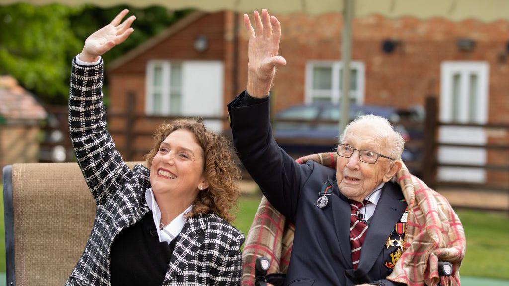 Hannah Ingram-Moore and Captain Sir Tom Moore wave at an RAF flypast in a garden