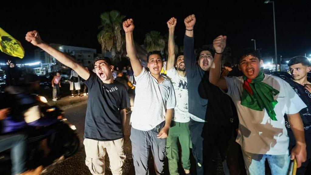 A crowd of men raise their arms in celebration