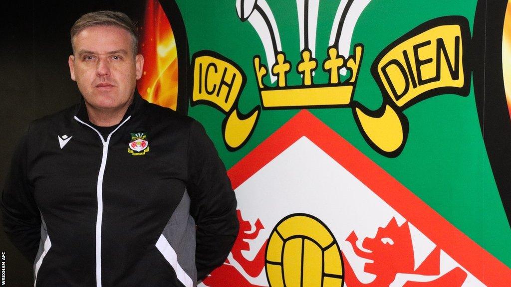 Andy Lowe in front of a Wrexham crest