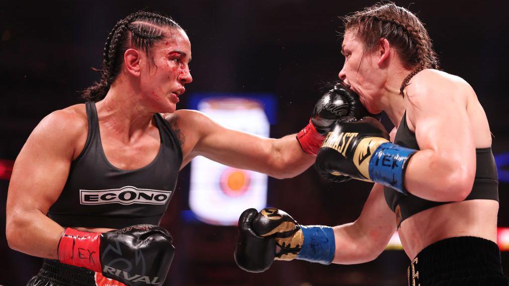 A cut Amanda Serrano lands a punch on the mouth of Katie Taylor