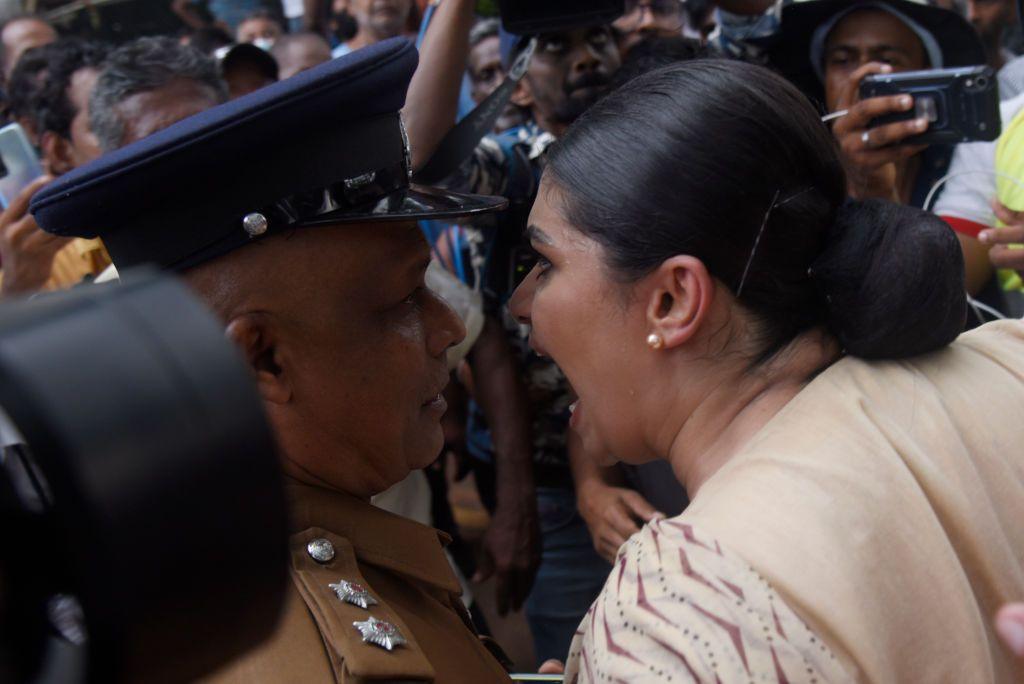 A women in a crowd shouts into the face of an officer 