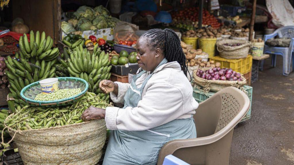 A vendor sorts green beans in her store at a market in Nairobi, Kenya, on Tuesday, July 25, 2023