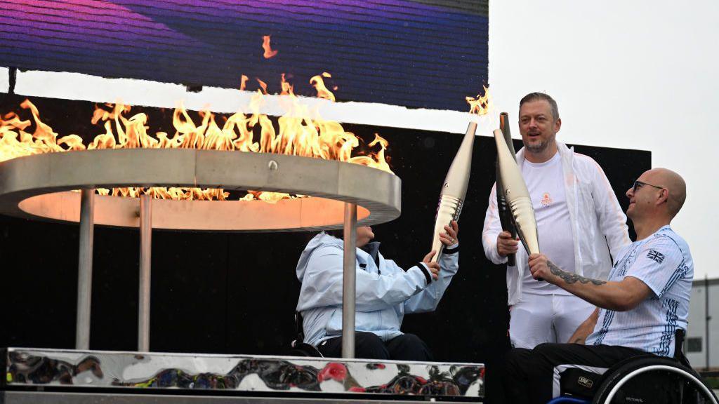 Helene Raynsford and Gregor Ewan lighting the Paralympic flame. 