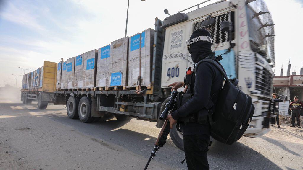 Humanitarian aid truck enters Rafah as a man dressed in black armed with a rifle stands watching