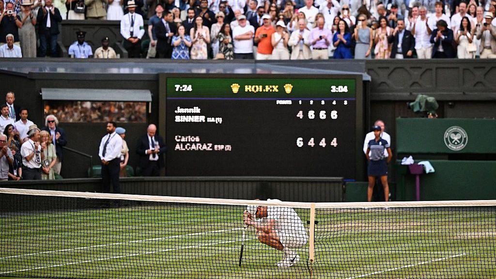 Jannik Sinner crouches to the ground after securing his first Wimbledon title