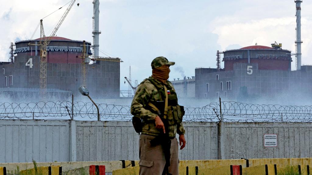 A serviceman with a Russian flag on his uniform stands guard near the Zaporizhzhia Nuclear Power Plant