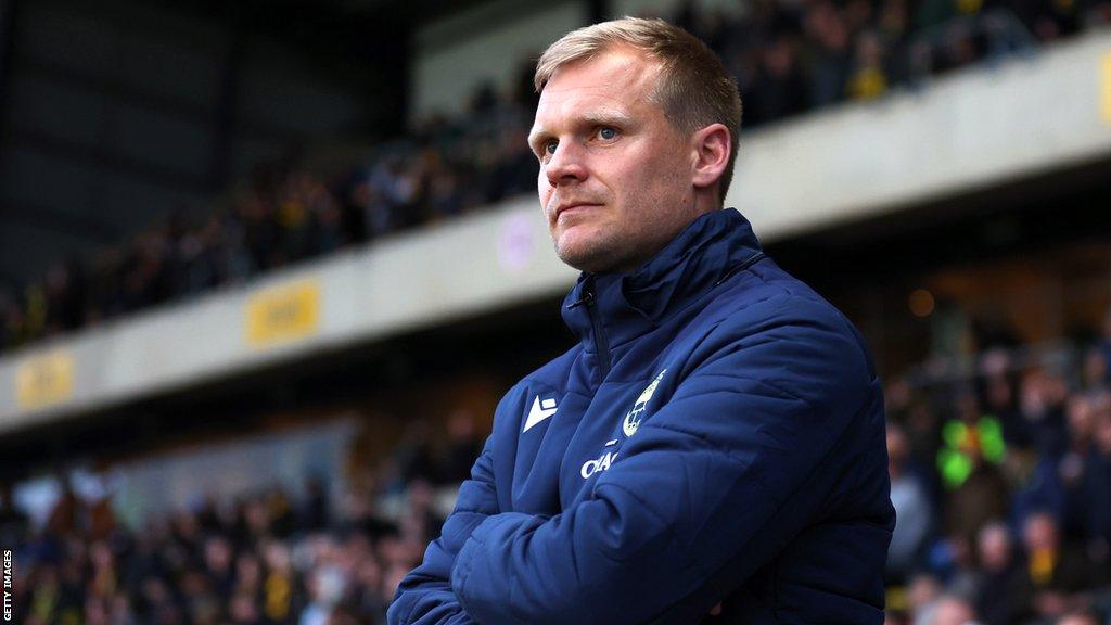 Oxford United boss Liam Manning watches his players on the field from the touchline during a League One match.