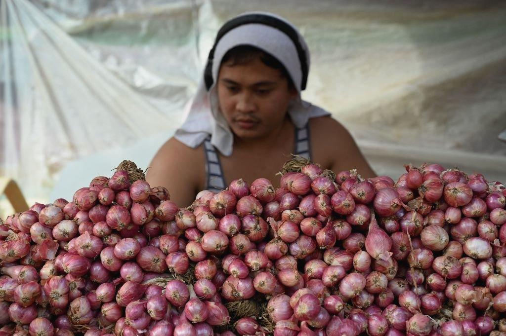 A vendor sells onions at a market in Manila.