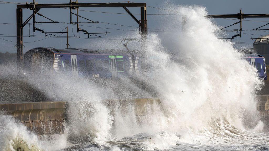 train getting splashed by sea.