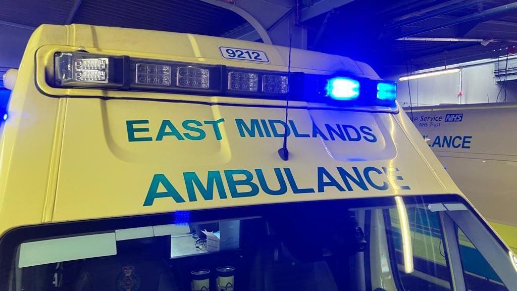 East Midlands ambulance on blue lights. The images shows the top of an ambulance cab, parked up next to another ambulance