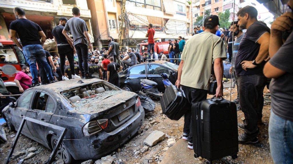 People gather in front of a building targeted by an Israeli strike in Beirut's southern suburbs on September 20