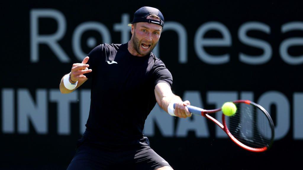 Liam Broady hits a tennis ball with his racquet