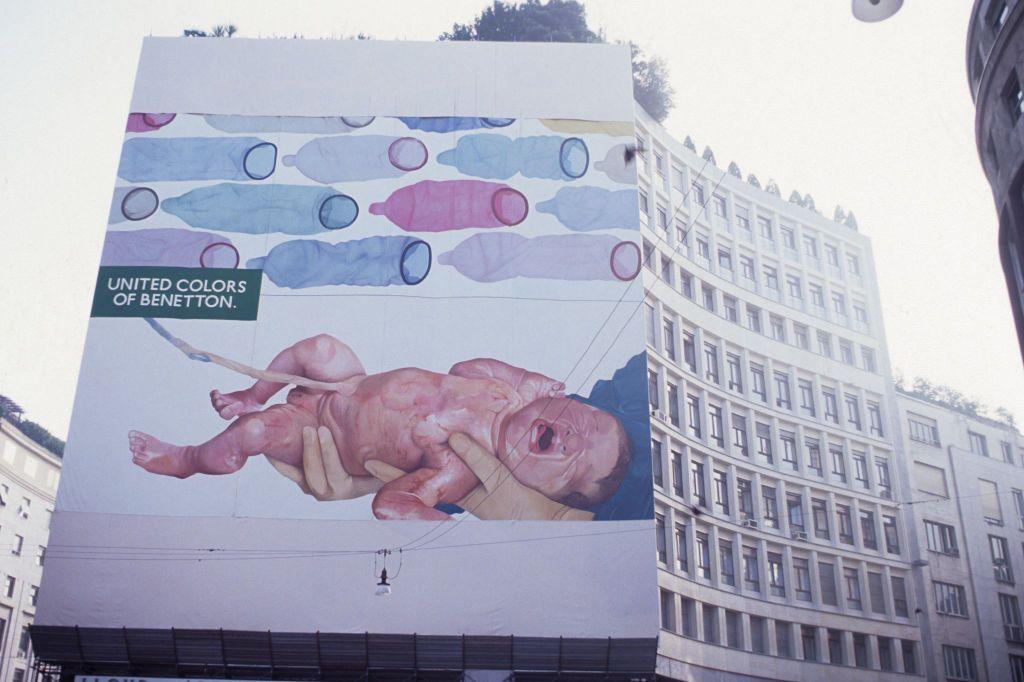 A newborn baby is depicted on a billboard crying, next to colourful condoms.