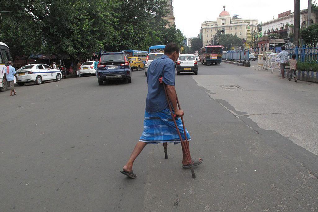 A man with a physical disability crosses a busy road in Kolkata, India, on July 7, 2026, as pedestrians and vehicles move through the urban landscape. (Photo by Rupak De Chowdhuri/NurPhoto via Getty Images)