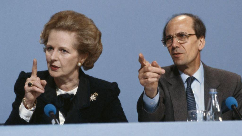 Margaret Thatcher sitting next to Norman Tebbit