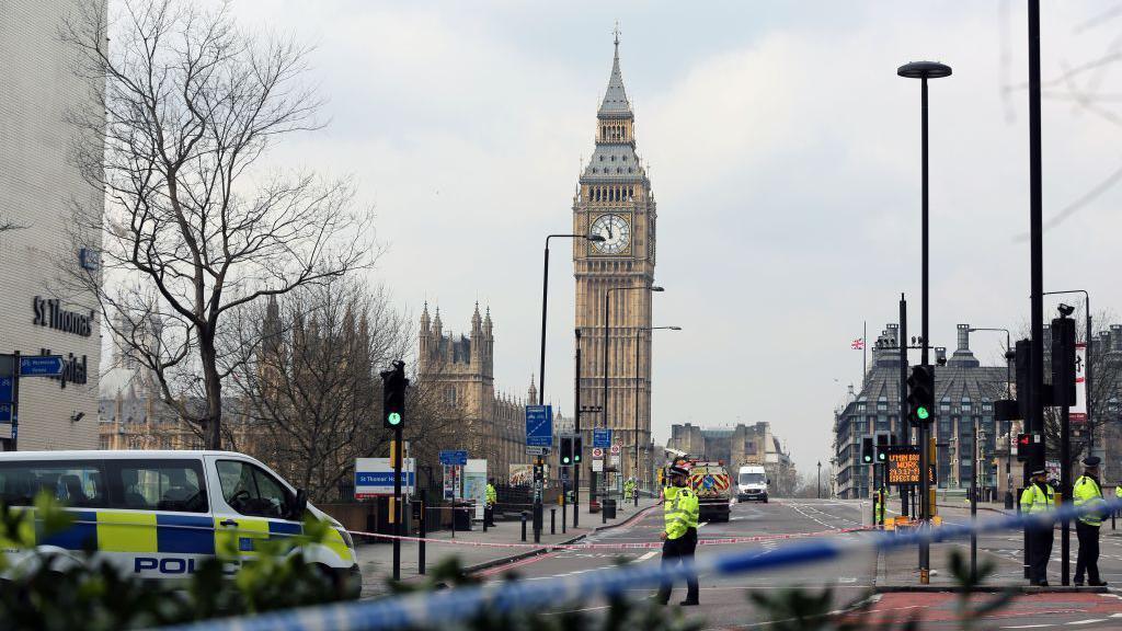 Police take security measures at Westminster Bridge after a car ran over people on the bridge during a terror attack. Police tape covers the entrance to the bridge and police vans and officers are seen in the vicinity.