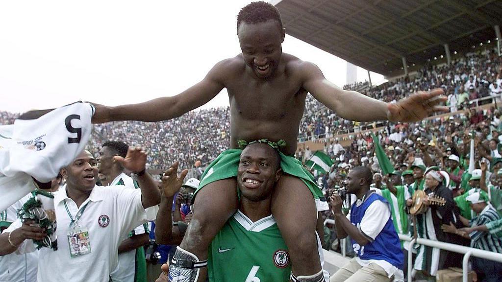 Tijani Babangida gets a shoulder ride from another video game legend, Taribo West