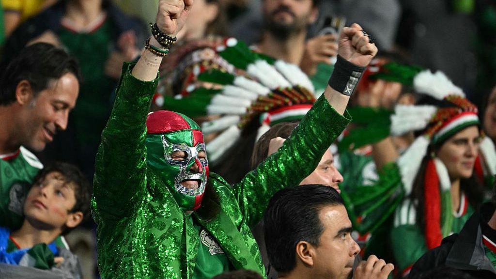 A Mexican fan wearing a lucha libre mask cheers.