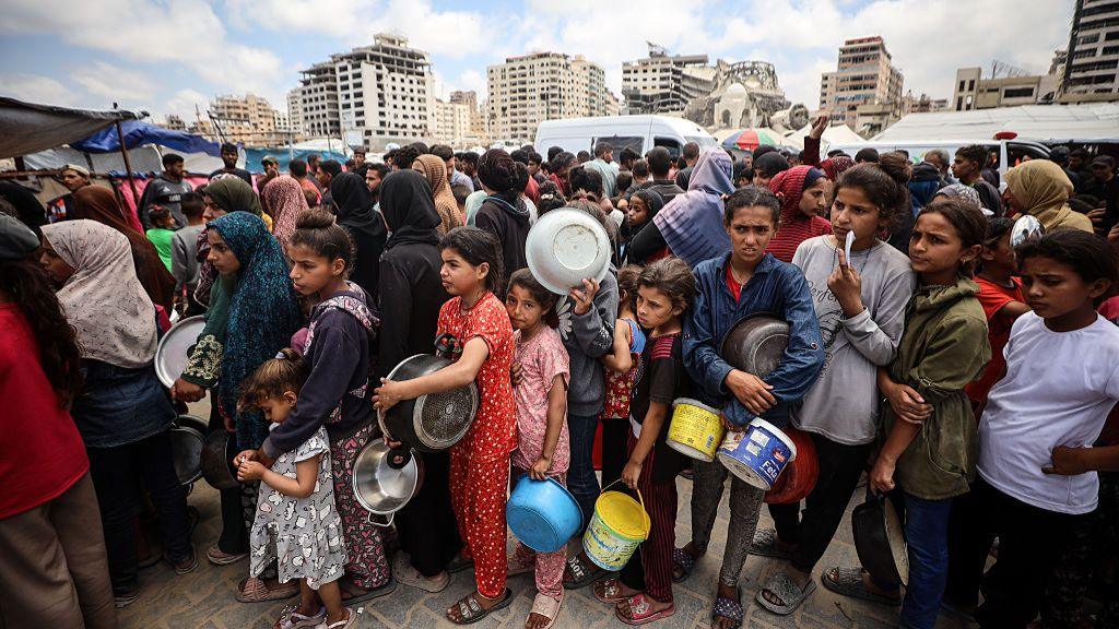 A large group of people, mainly children, queue for food in Gaza 