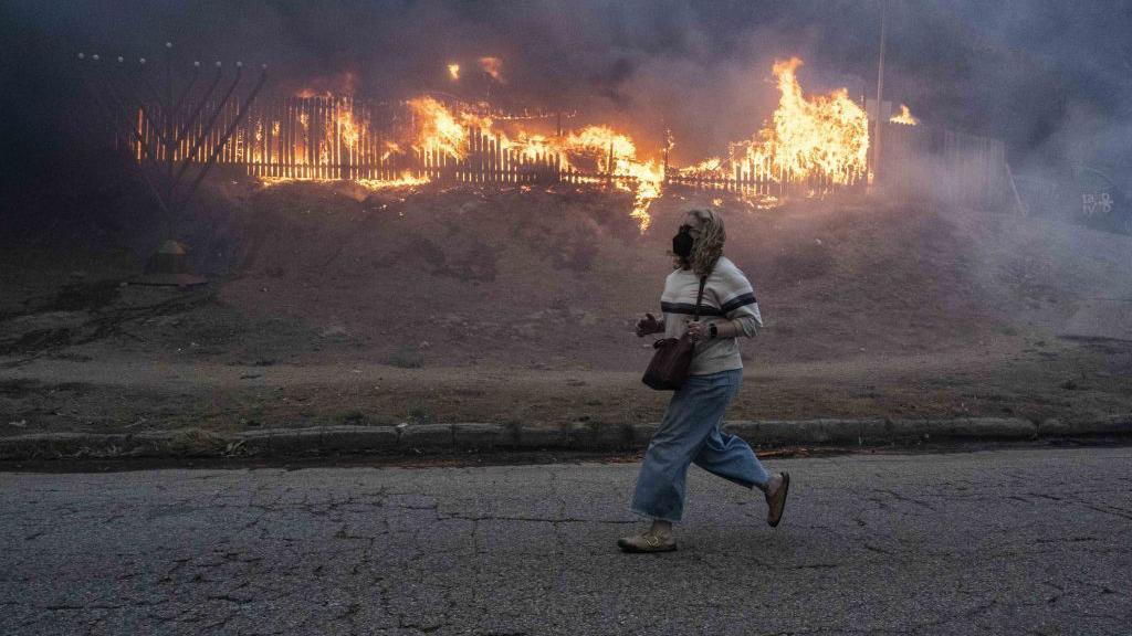 A person runs past a building on fire