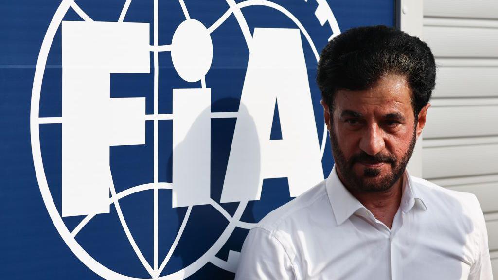 Mohammed Ben Sulayem stands in front of an FIA sign 