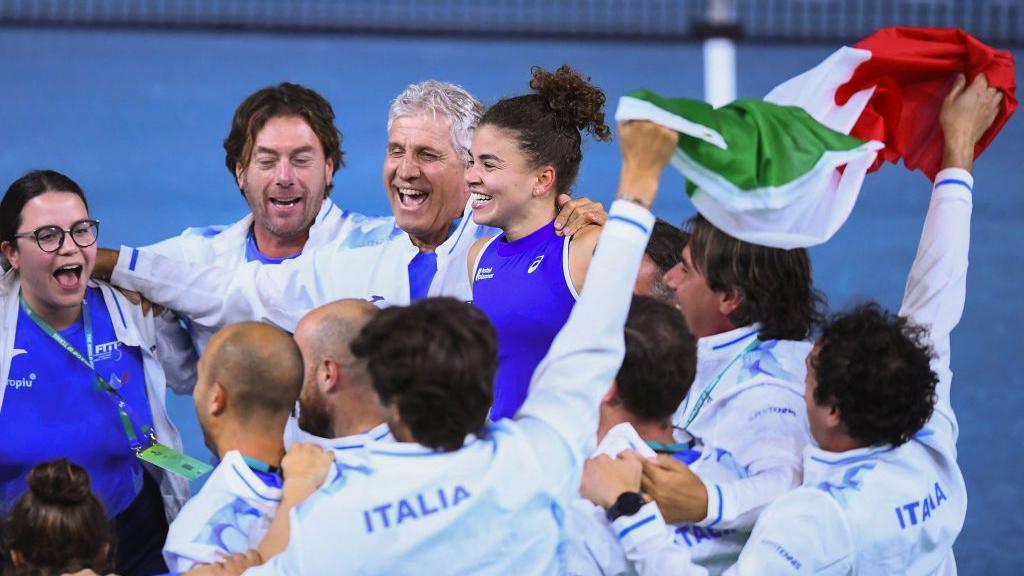 Italy's Jasmine Paolini (C top) celebrates with Team Italy teammates after defeating Slovakia's Rebecca Sramkova