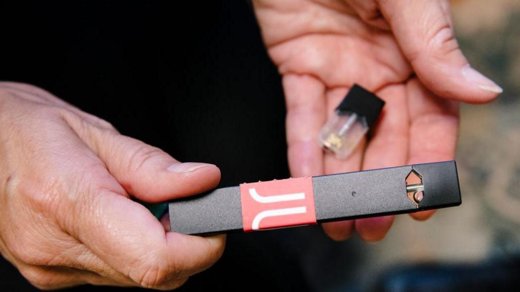 A woman holds a Juul vaporizer and cartridge she uses to help teach students the dangers of vaping, in her office at Washington High School in San Francisco, Calif, on Thursday, September 5, 2019. 