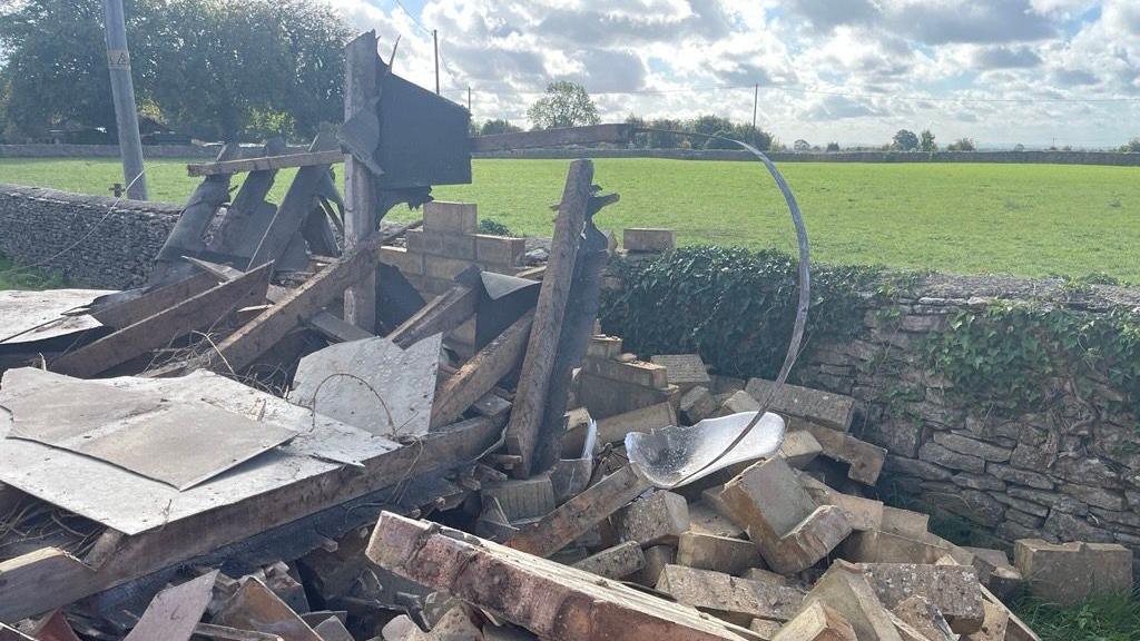 A close-up image of collapsed stonework from the bus shelter, with a white seat visible at the top oft he pile of rubble