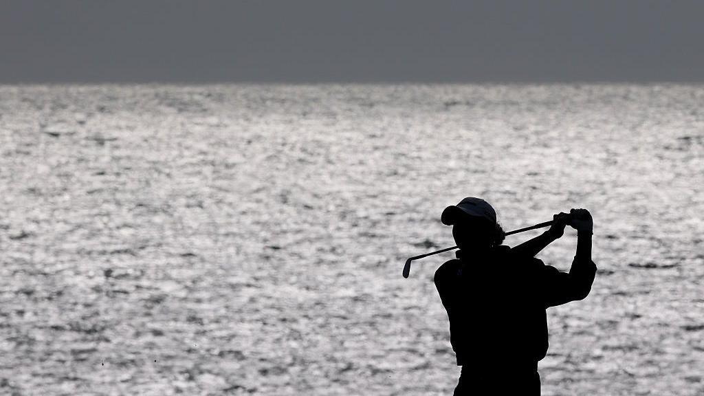 A silhouette image of Charley Hull as she plays a shot on 18 at Royal Porthcawl