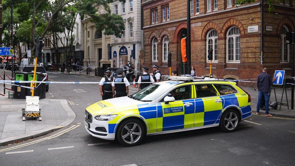 A police car and officers gather on a street in London